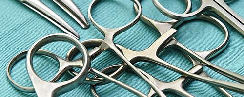 Pinces et ciseaux chirurgicaux disposés sur un tissu bleu stérile dans un environnement médical