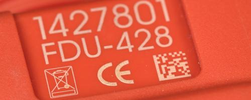 Marquage Datamatrix sur une pièce en plastique rouge avec référence gravée et symboles CE