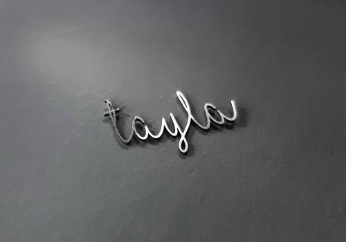 Découpe laser du prénom "Tayla" en métal dans un style manuscrit, utilisé dans la personnalisation de bijoux.