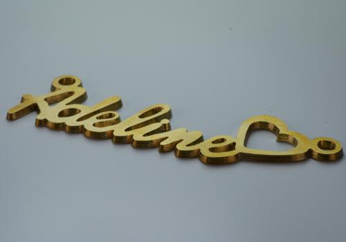 Découpe en métal doré portant l'inscription "Adeline" en forme de cœur, réalisée pour la personnalisation du bijou